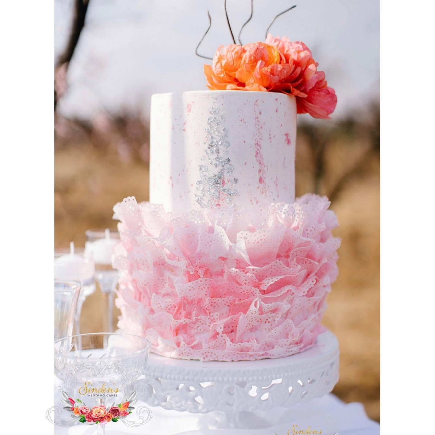 White cake with pink ruffles and matching cupcakes