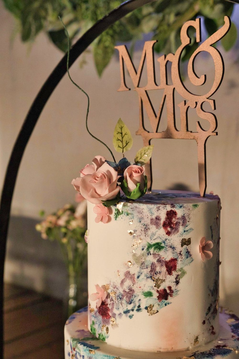 White cake with greenery and a Mr and Mrs topper