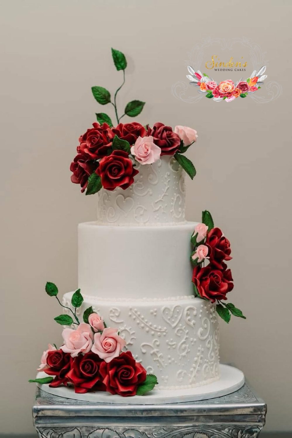 White wedding cake adorned with deep burgundy roses