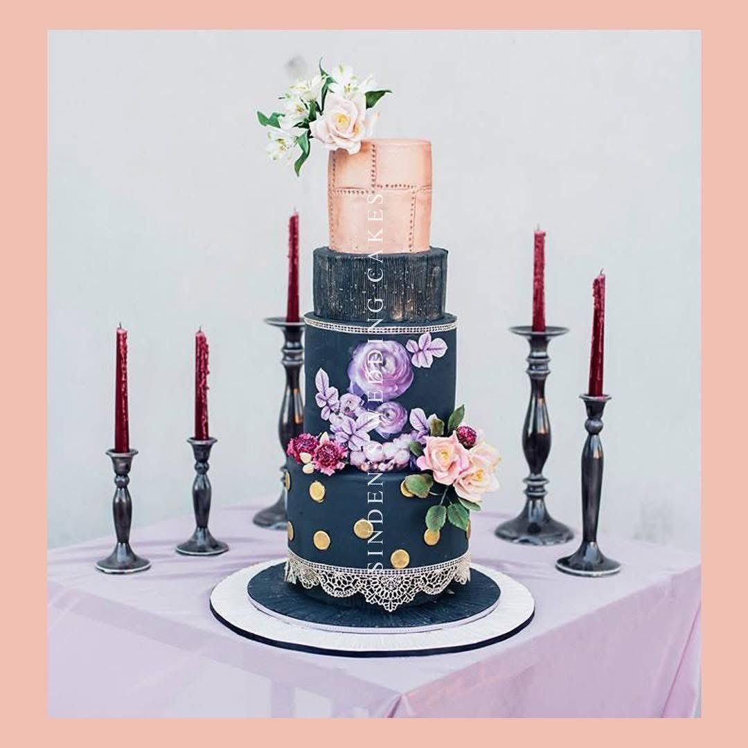 Navy and gold wedding cake with dark candles and flowers